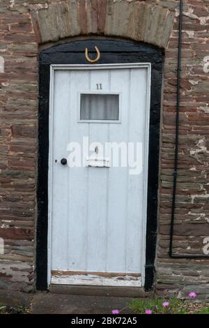 une vue rapprochée d'une porte d'entrée blanche avec une chaussure de cheval en haut pour une bonne chance Banque D'Images