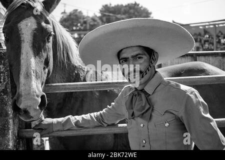 Portrait d'un cowboy mexicain devant un cheval sauvage dans une cage prête à être utilisé dans un événement de 'charreria'. Charrerias sont l'équivalent mexicain de rode Banque D'Images