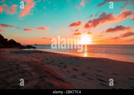 un coucher de soleil tropical accueillant sur une plage de vacances avec de nombreuses empreintes de pas sur la rive Banque D'Images