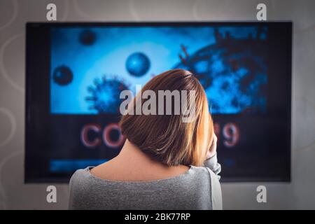 Une femme regarde une émission de télévision sur la distribution de СOVID 19. Le concept d'un état dépressif. Banque D'Images