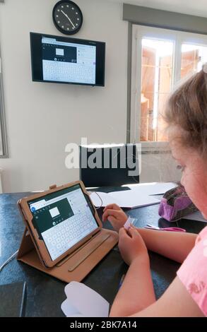 France, Loiret (45 ans), Covid-19 verrouillage français le 04/27/2020, jeune fille de 7 ans au   cours de la classe scolaire virtuelle à la maison à l'aide d'une tablette à distance Banque D'Images