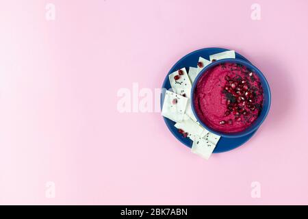 houmous composé de betteraves, de pois chiches dans des bols. sur fond rose, avec des chips de pain. espace de copie. plat Banque D'Images