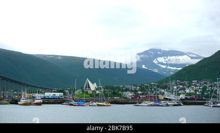 Vue magnifique sur la ville de Tromsø, Norvège. Port avec bottes, un pont près de l'église, des montagnes enneigées en arrière-plan Banque D'Images