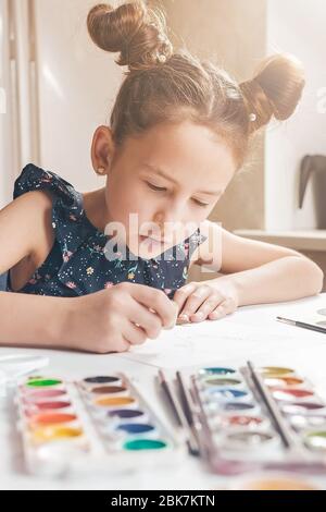 Jolie fille dessine avec des crayons et des peintures. Activités en quarantaine pour les enfants. Prise de vue verticale Banque D'Images