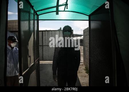 Jisr Al Shughur, Syrie. 02 mai 2020. Un homme porte un masque facial alors qu'il est vaporisé désinfectant avant d'entrer dans un centre d'isolement sanitaire qui a été établi aux frontières syro-turques afin de placer les personnes venant de Turquie à Idlib comme mesure préventive contre la propagation de la maladie du coronavirus (COVID-19). Le centre est supervisé par une équipe médicale formée à toutes les mesures à prendre pour traiter les expatriés puisque le centre a reçu plus de 600 personnes jusqu'à présent et la période d'isolement est de 15 jours. Crédit: Anas Alkharboutli/dpa/Alay Live News Banque D'Images