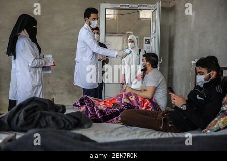 Jisr Al Shughur, Syrie. 02 mai 2020. Un medic contrôle la température d'un homme à l'intérieur d'un centre d'isolement sanitaire qui a été établi aux frontières syro-turque afin de placer les personnes venant de Turquie à Idlib comme mesure préventive contre la propagation de la maladie du coronavirus (COVID-19). Le centre est supervisé par une équipe médicale formée à toutes les mesures à prendre pour traiter les expatriés puisque le centre a reçu plus de 600 personnes jusqu'à présent et la période d'isolement est de 15 jours. Crédit: Anas Alkharboutli/dpa/Alay Live News Banque D'Images