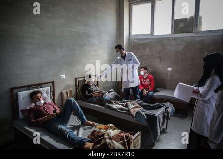 Jisr Al Shughur, Syrie. 02 mai 2020. Un medic contrôle la température d'un homme à l'intérieur d'un centre d'isolement sanitaire qui a été établi aux frontières syro-turque afin de placer les personnes venant de Turquie à Idlib comme mesure préventive contre la propagation de la maladie du coronavirus (COVID-19). Le centre est supervisé par une équipe médicale formée à toutes les mesures à prendre pour traiter les expatriés puisque le centre a reçu plus de 600 personnes jusqu'à présent et la période d'isolement est de 15 jours. Crédit: Anas Alkharboutli/dpa/Alay Live News Banque D'Images