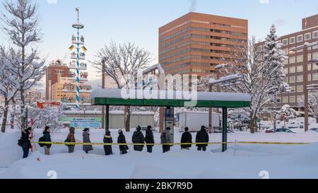 Passagers attendant le bus dans la neige, Sapporo, Japon Banque D'Images