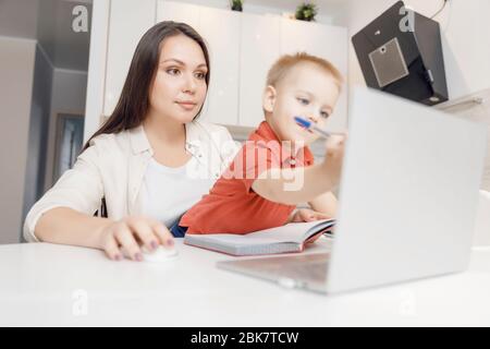 Belle femme aide son fils à apprendre à écrire des lettres d'alphabet. Concept d'apprentissage en ligne Banque D'Images