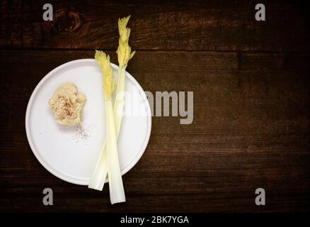 Céleri de branche frais avec houmous sur table en bois Banque D'Images