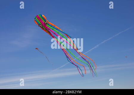 Rubans colorés et figurines en cerf-volant accrochés sur des poteaux et volantes sur fond bleu kite festival Banque D'Images