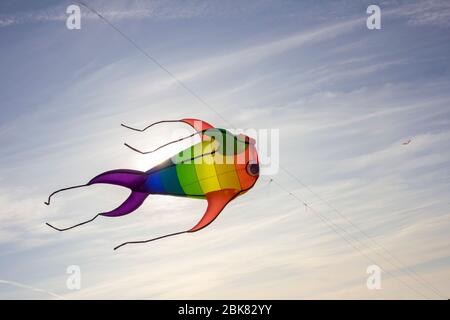 Rubans colorés et figurines en cerf-volant accrochés sur des poteaux et volantes sur fond bleu kite festival Banque D'Images