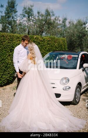 Belle mariée et marié front pendu à forehrad et tenant les mains devant le convertible à la vieille villa en Italie, en Toscane, près de Florence Banque D'Images