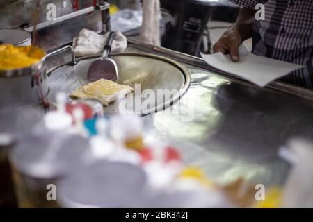 Préparation de savoureuses crêpes traditionnelles thaïlandaises sur un comptoir de rue. Les mains de sexe masculin y frire une crêpe à l'huile. Spécialité locale. Banque D'Images