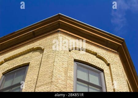 Vue vers le haut d'un toit orné corniche sur un bâtiment traditionnel en briques anciennes avec fond bleu ciel Banque D'Images