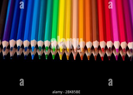 De nombreux crayons de couleur différents se reflètent sur fond noir Banque D'Images