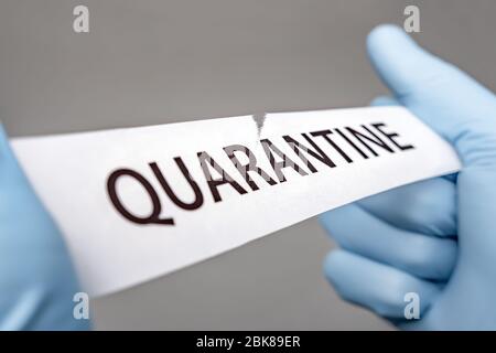 Les mains dans des gants médicaux déchirent un morceau de papier avec LA QUARANTAINE imprimée dessus. Covid-19 Wuhan Novel Coronavirus pneumonie: COVID-19. Virus dangereux Banque D'Images