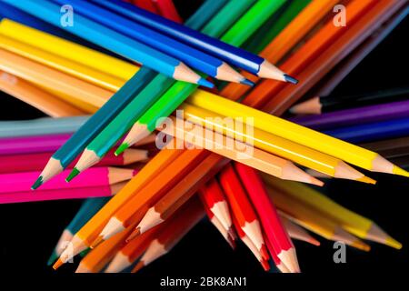 De nombreux crayons de couleur différents se reflètent sur fond noir Banque D'Images