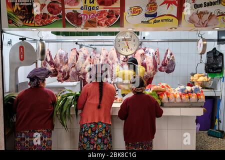 Les femmes vêtues de vêtements traditionnels colorés achètent de la viande dans un marché local Banque D'Images