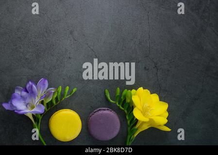 Carte de vœux colorée concept.bouquet de fleurs Freesia et macarons colorés sur fond de pierre grunge noire. Affiche pour les femmes jour, mariage Banque D'Images
