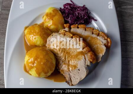 Viande fine - rôti de porc avec craquelle, boulettes de pommes de terre et chou rouge Banque D'Images