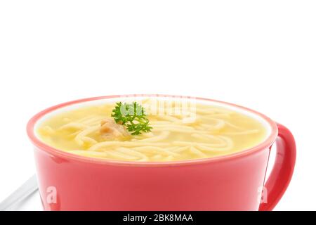 Soupe de nouilles au poulet dans un mug en céramique orange photographié sur fond blanc avec un grand espace de copie. Banque D'Images