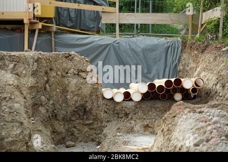 un arbre de construction sur un chantier de construction partiellement couvert par une bâche. Il y a des tuyaux sur le sol et des barrières en bois autour de l'arbre comme un méd Banque D'Images