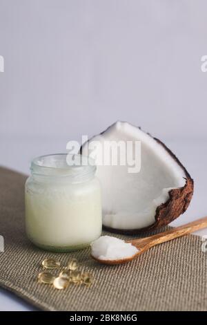 coconut oil in glass bottle and vitamin e with wooden spoon and white background Banque D'Images