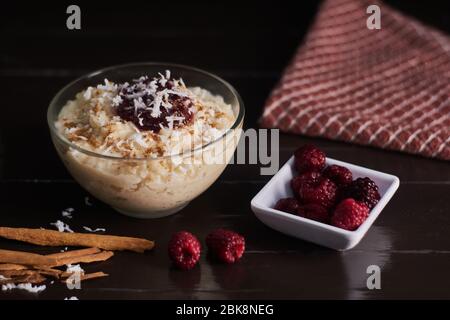 Riz au lait de cannelle, noix de coco, confiture et framboises fraîches sur fond de bois brun Banque D'Images