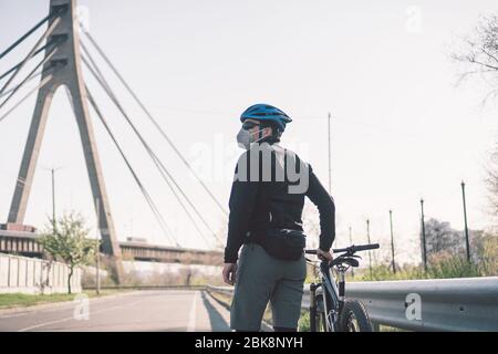 Cycliste dans la ville blanchie par le smog dans le masque N95. Pollution de l'air. Ville industrielle. Homme dans le masque de la poussière. Guy dans respirateur avec filtre pm 2.5. Thème Covid Banque D'Images