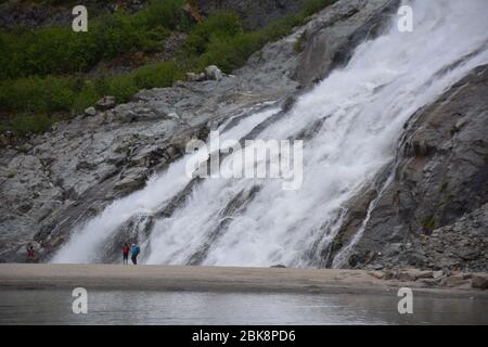 Les touristes se tiennent près des chutes de Nugget au glacier Mendenhall près de Juneau, en Alaska. Banque D'Images