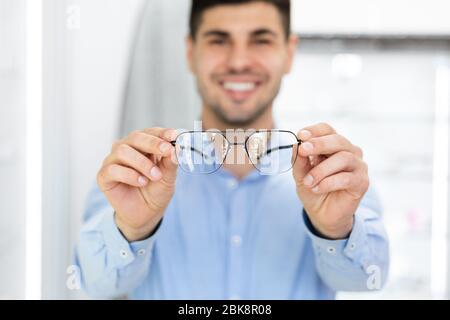 Portrait de beau jeune gars montrant des lunettes Banque D'Images