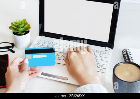 Femme mains tenant une carte de crédit et utilisant l'ordinateur pour les achats en ligne entrer le code sécurisé sur le clavier. Écran d'ordinateur portable vierge, modèle de conception. Banque D'Images