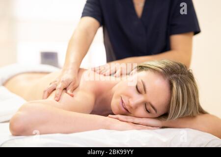 Femme posée sur une civière recevant un massage du dos.