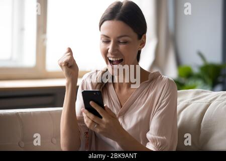 Une femme excitée qui regarde l'écran du téléphone et célèbre la victoire Banque D'Images