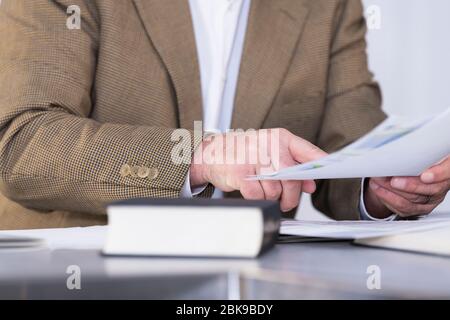 Gros plan sur les mains des hommes tenant un document et le pointant vers lui avec un livre hors de l'intérêt à l'avant. Le lieu de travail et le concept d'affaires. Banque D'Images