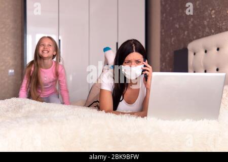 Mère travaillant de la maison avec des enfants. Quarantaine et école fermée pendant l'éclosion de coronavirus. Les enfants font du bruit et dérangent la femme au travail. Homeschoo Banque D'Images