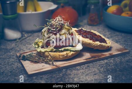 Délicieux hamburger végétarien fait maison avec source de barbecue et oniens sur plaque de bois Banque D'Images