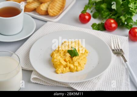 Œufs brouillés, omelette, vue latérale. Petit déjeuner avec œufs poêlés, verre de lait Banque D'Images