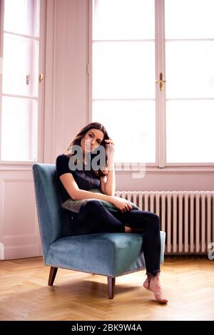 Photo pleine longueur de belle femme se reposant sur le fauteuil à la maison. Banque D'Images