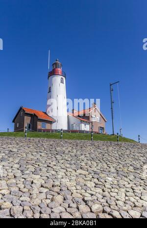 Phare blanc et maisons sur le haut de la digue à Urk, Pays-Bas Banque D'Images