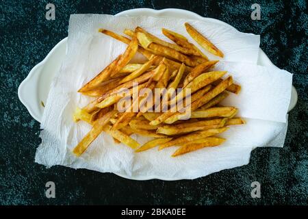 Pommes de terre aux frites fines et assaisonnées cajun avec serviettes en papier. Prêt à servir de la nourriture maison. Banque D'Images