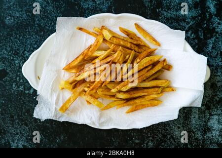 Pommes de terre aux frites fines et assaisonnées cajun avec serviettes en papier. Prêt à servir de la nourriture maison. Banque D'Images