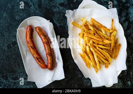 Saucisse maison avec pommes de terre aux frites skinny dans une serviette en papier et en plaque également appelée Salchilapa péruvienne. Restauration rapide. Banque D'Images