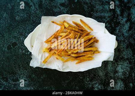 Pommes de terre aux frites fines et assaisonnées cajun avec serviettes en papier. Prêt à servir de la nourriture maison. Banque D'Images