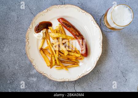 Saucisse maison avec pommes de terre aux frites skinny dans la plaque avec verre de bière également appelé Salchilapa péruvien. Restauration rapide. Banque D'Images