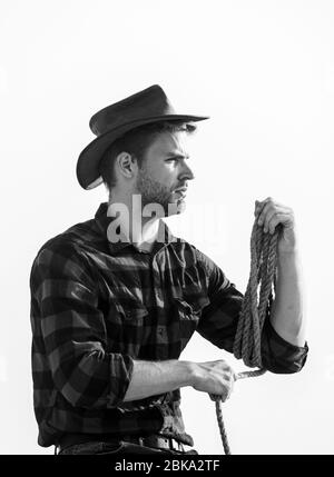 Concept de l'agriculture. Bel homme en chapeau et costume de style rustique. Garder ranch. La vie au ranch. Cowboy avec lasso corde fond de ciel. Agriculteur réfléchie réflexion sur l'entreprise. Ranch travailleur. Eco farm. Banque D'Images