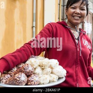 Hoi an Vietnam 17 octobre 2020; femme vendeur de rue souriant et tenant plateau d'arachides et de popcorn en sac à vendre dans la rue de la ville Banque D'Images