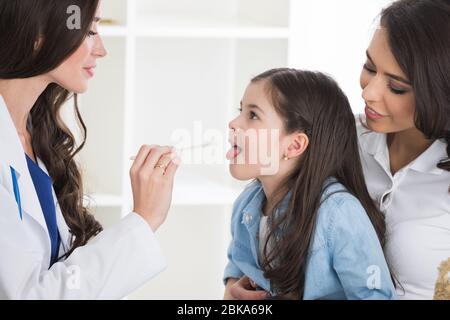 Petite fille ayant un examen de gorge par pédiatre à la vérification en clinique Banque D'Images