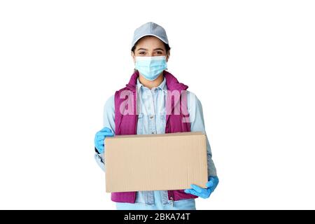 La femme hispanique courier porte des gants de masque portant une boîte de livraison isolée sur blanc. Banque D'Images